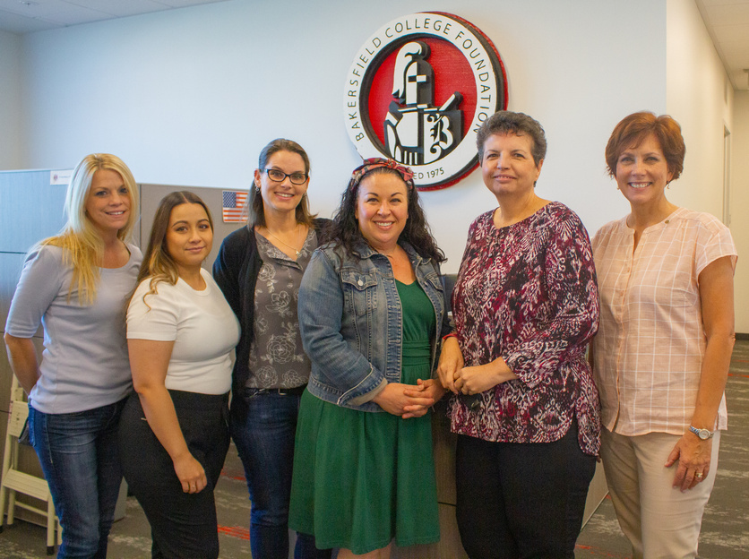 Six women in front of the Foundation logo sign.