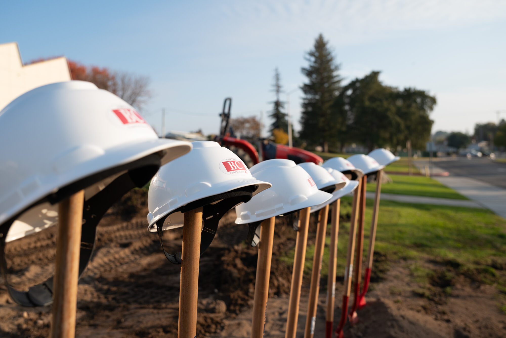 Hard hats placed on top of shovels that are placed in dirt