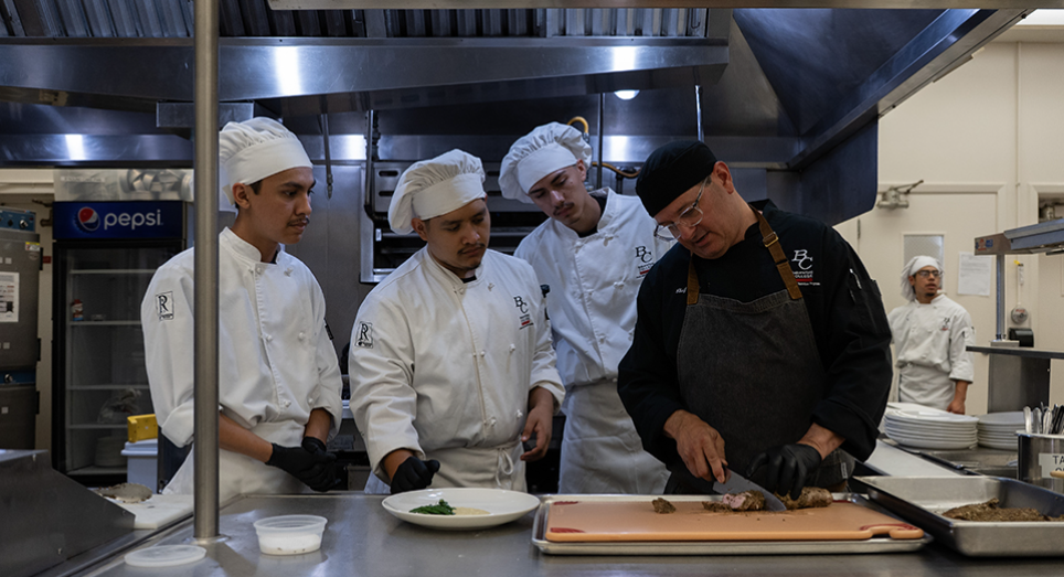 Chef showing culinary students how to cut 