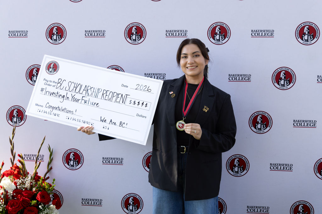 A scholarship recipient holding up a giant check