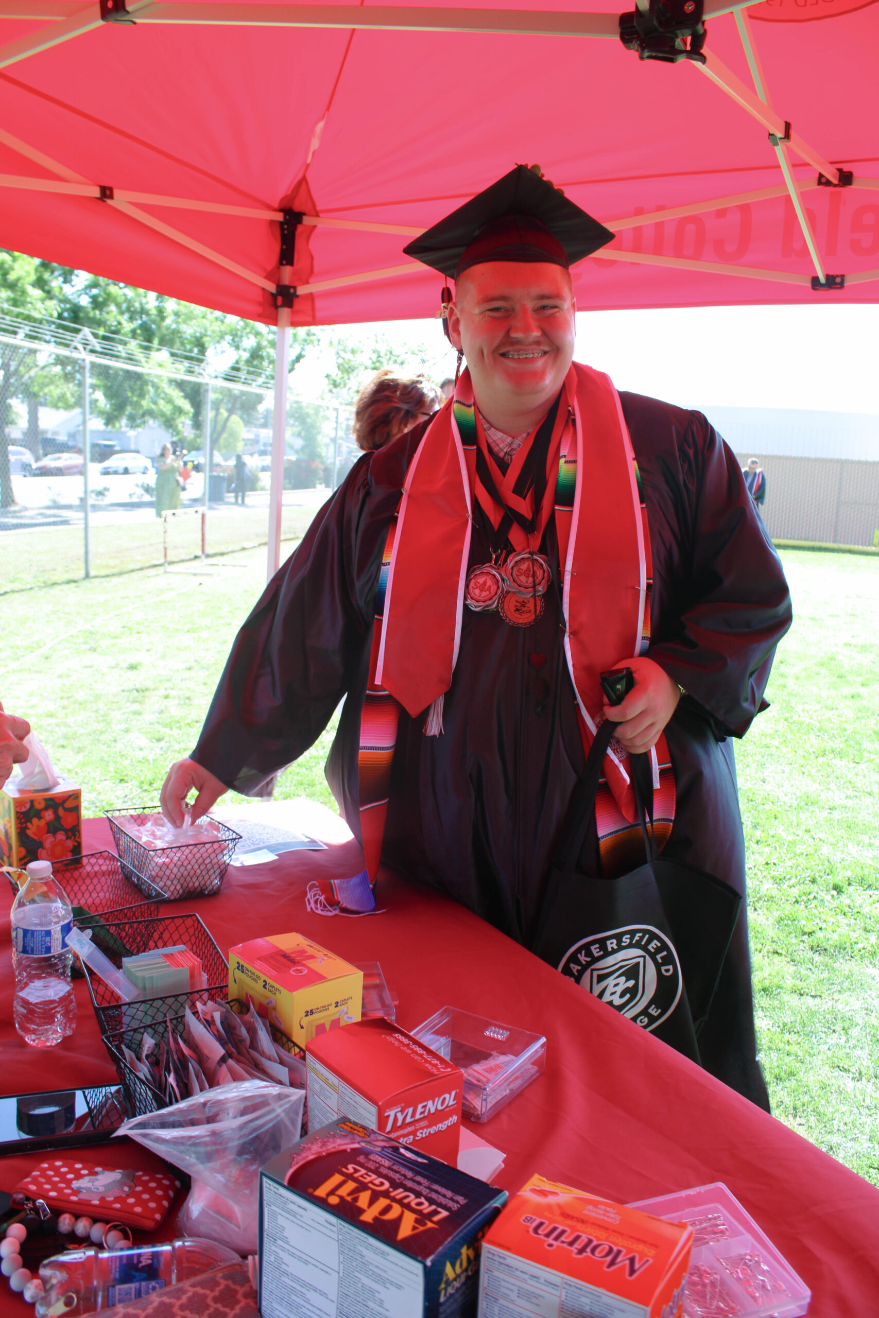 A graduate posing while he grabs essentials from a table