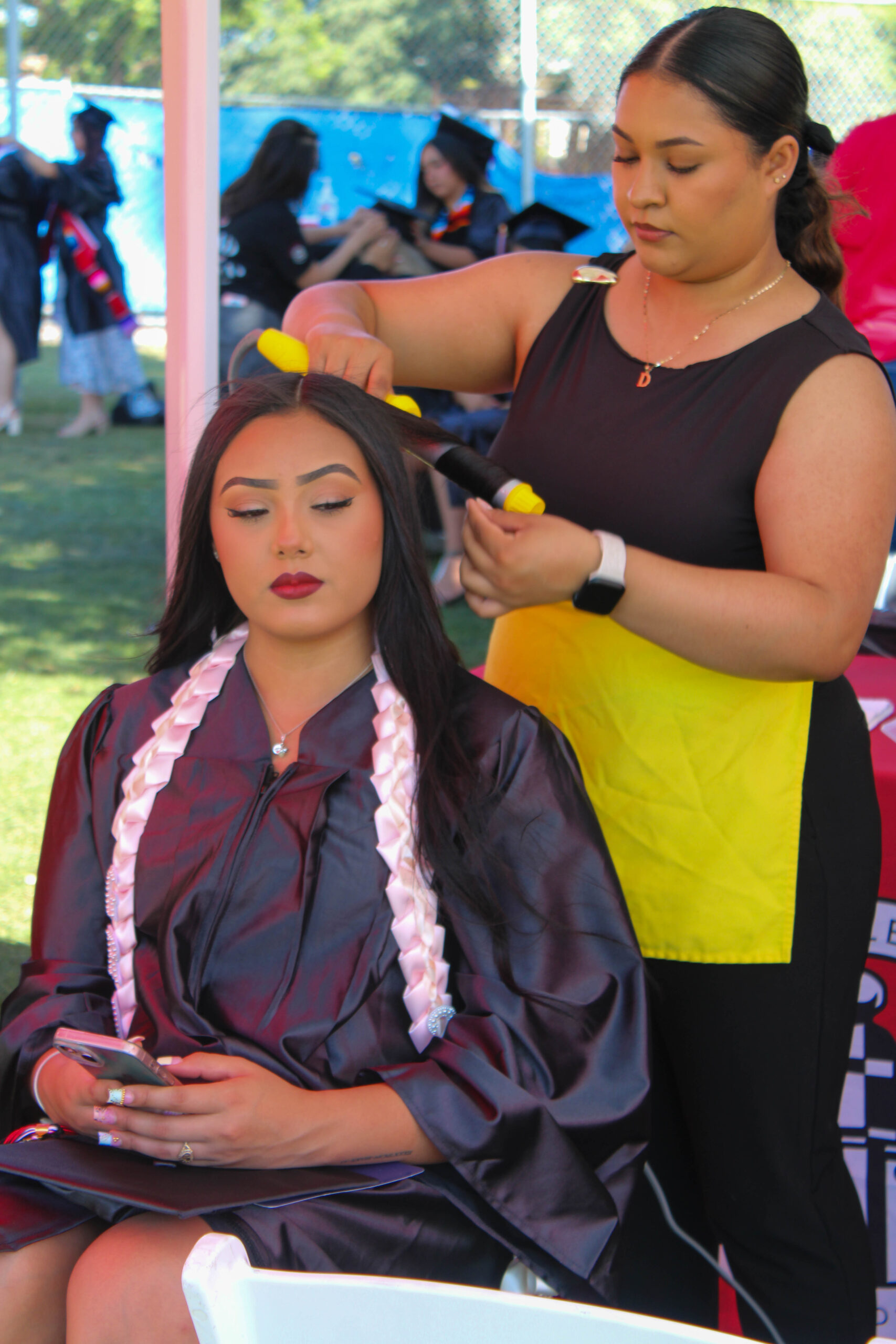 A Drybar employee curling a graduates hair