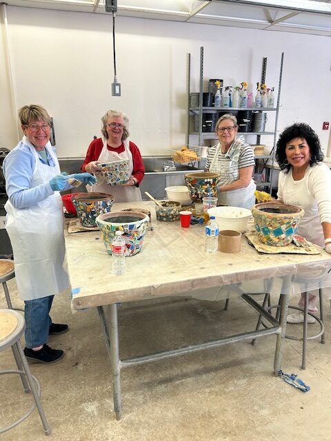 Four ladies standing around a table doing pottery