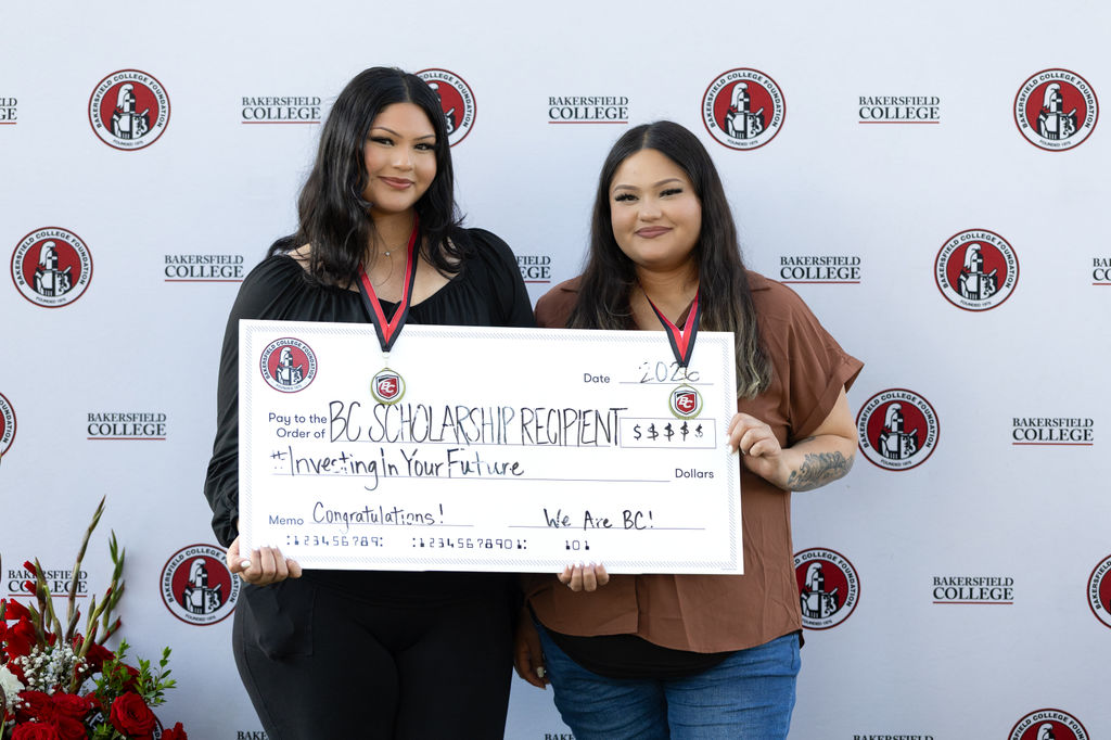 Two BC scholarship recipient hold a ceremonial check.