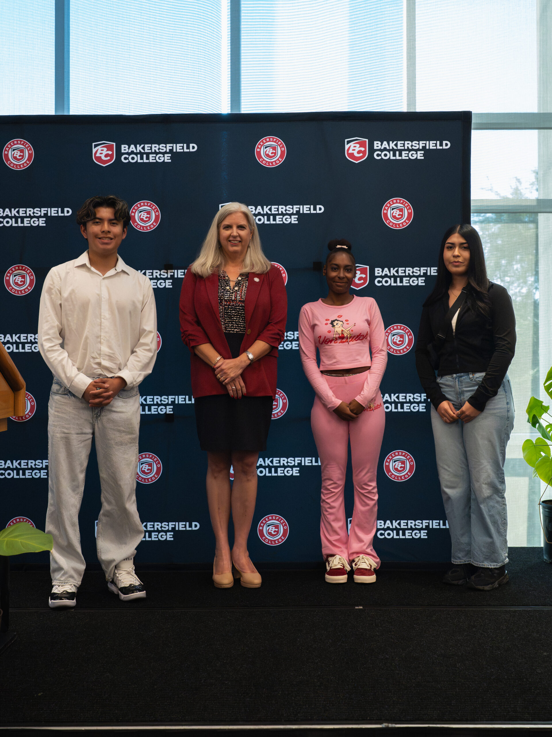 President Stacy Pfluger posing with three students