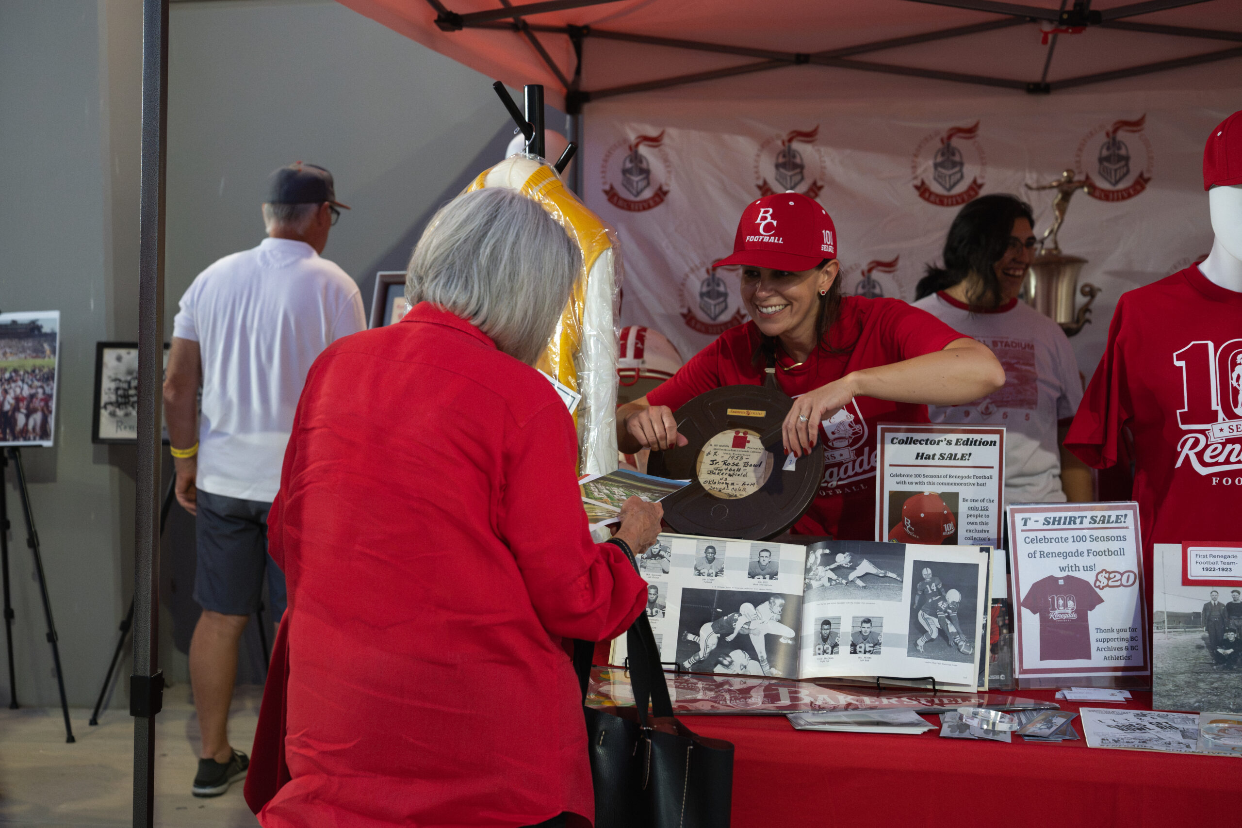 BC Archives representative shows a historic game reel to a visitor at the football display