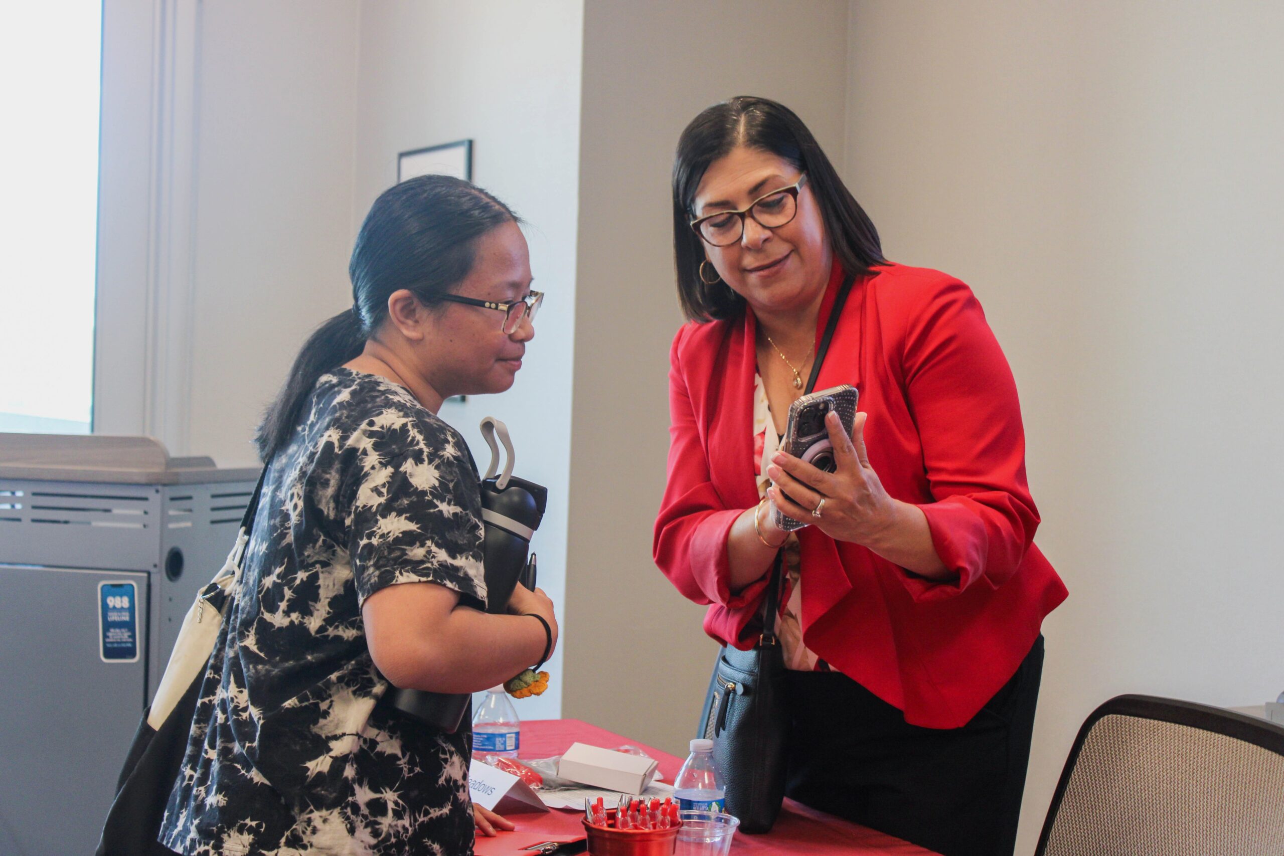 Two women networking and looking at a phone together