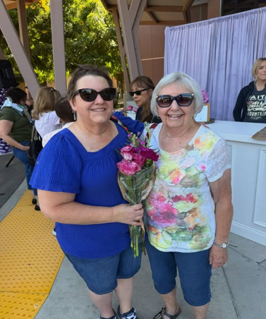 Two women with sunglasses holding a bouquet of flowers.